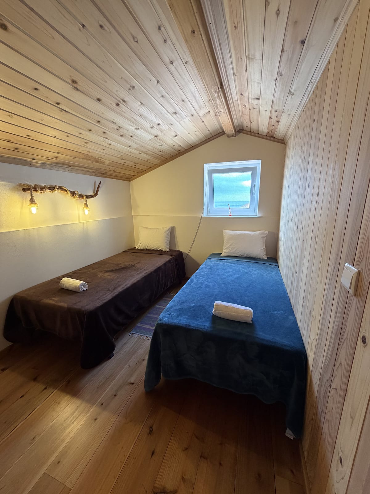 Second bedroom with two single beds and a window facing the sea
