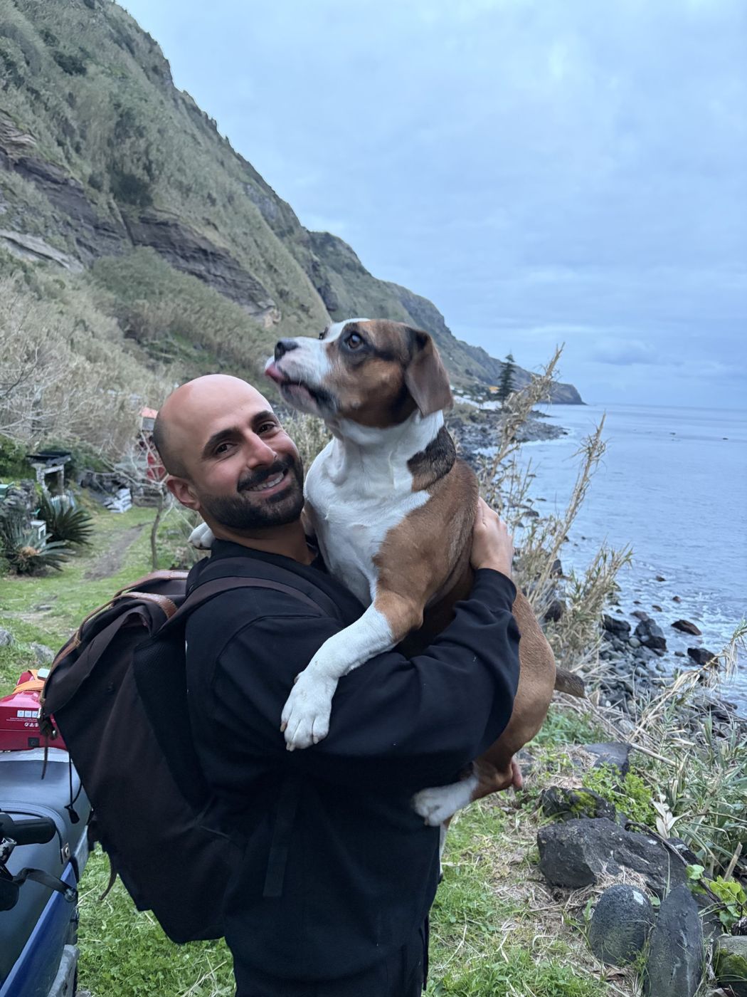 Ramsen smiling and holding the dog on the path above the sea