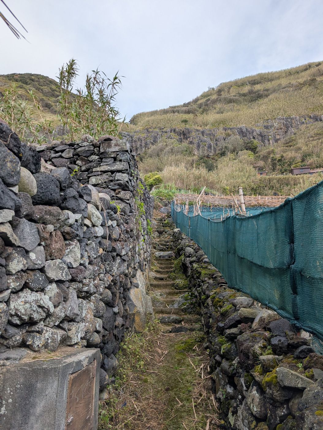Narrow stone stairway between old lava-rock walls
