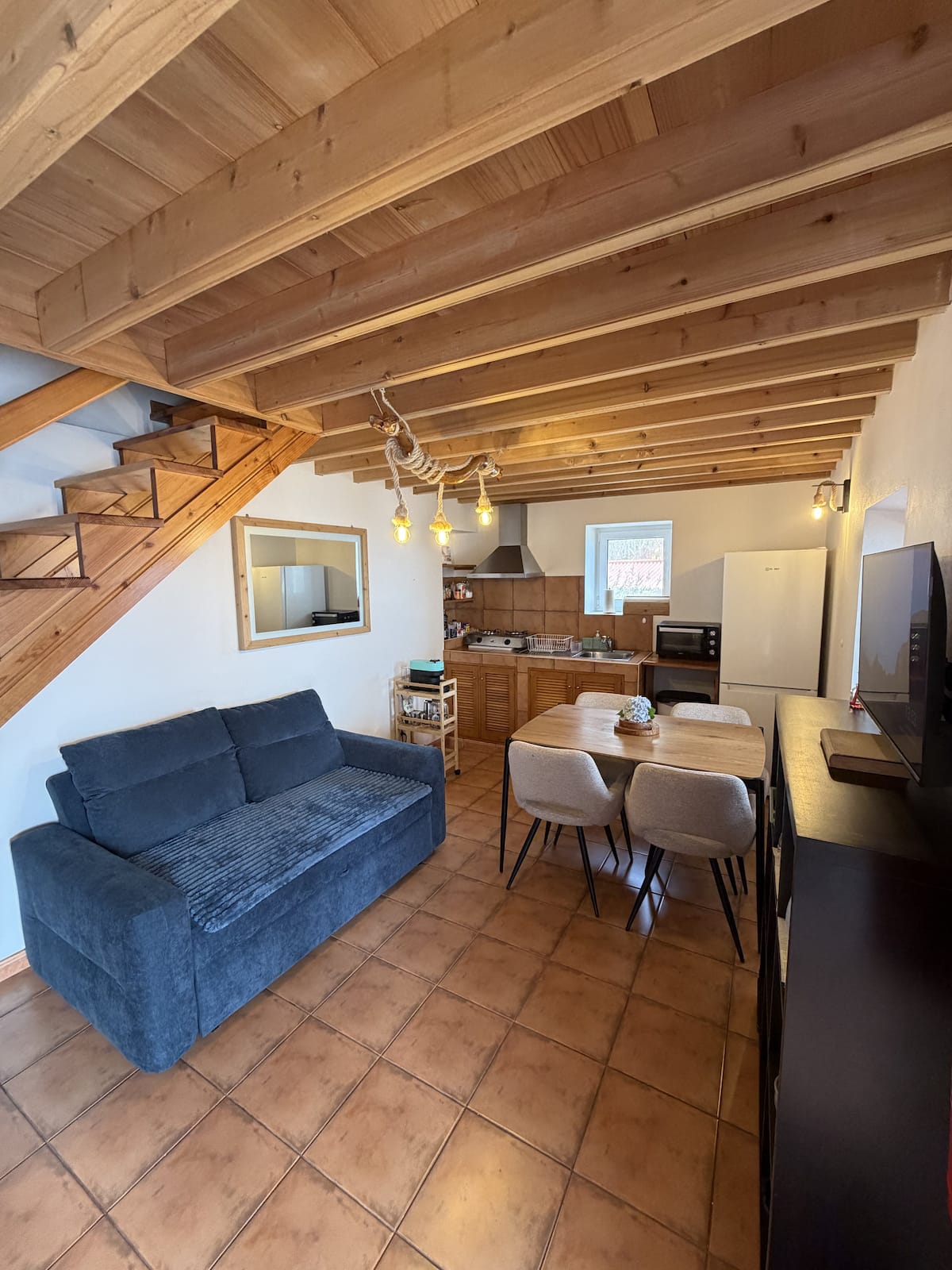 The living room and kitchen, wood beams overhead, stairs up to the loft