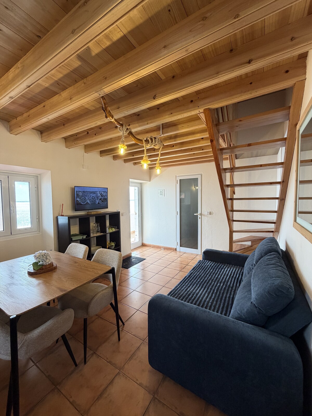 Living room with TV, dining table, and staircase to the loft